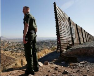 Border Patrol Officer and old barrier overlooking valley