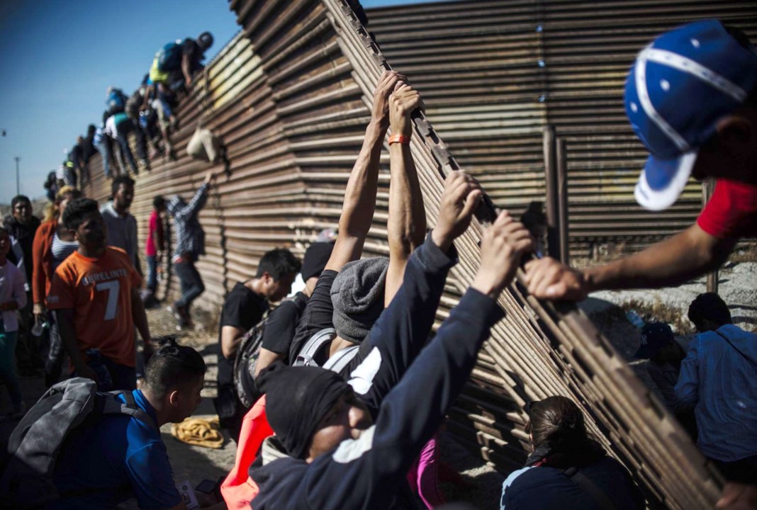 Migrants tearing down barrier wall